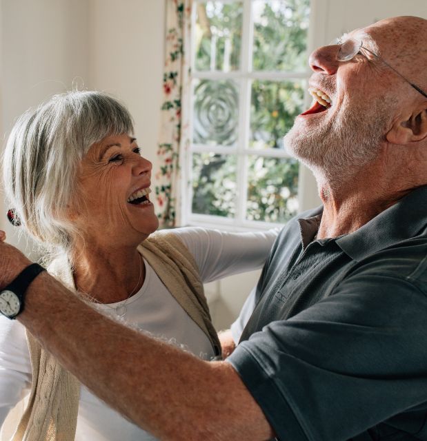 Old couple dancing in the kitchen and laughing